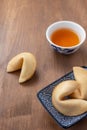 Aerial view of fortune cookies in plate and china cup with tea, on wooden table, with selective focus, in vertical, Royalty Free Stock Photo