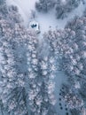 Aerial view of frosted coniferous forest and a small gazebo in the park