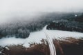 Aerial view of frosty forest road and fog above forest