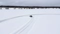 Aerial view of a frozen snow and ice covered lake with bending track. Clip. Drifting car on a winter day. Royalty Free Stock Photo