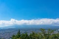 Aerial view of Fujiyoshida town and Mount Fuji peaking over clouds on sunny day