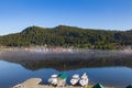 Aerial view of the gazebos in the Altai Mountains on the shore of Lake Teletskoye with three boat moored near the shore river with