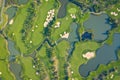 Aerial view of a golf course fairway and green with sand traps, trees and golfers