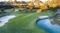 Aerial view of golf course green with flag, bunkers and dam water hazards surrounded by trees in background Royalty Free Stock Photo