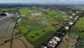 Aerial view of green croplands with a city and the sky in the background.