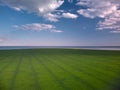 Aerial view of green field near blue sea with blue cloudy sky in evening Royalty Free Stock Photo