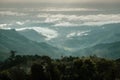 Aerial view of green forest with sea of fog and clouds around mountain range. Royalty Free Stock Photo