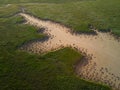 Aerial view of green grass around a sandy ravine formed by rain