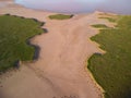Aerial view of green grass around a sandy ravine formed by rain