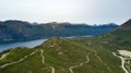 Aerial view of the green hill and mountainous lake surrounded by high mountain during summer time.