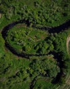 Aerial view of green meadow fields with zigzag channel water