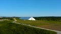 Aerial view of a green meadow and a white industrial greenhouse on blue sky background. Video. People walking on a Royalty Free Stock Photo