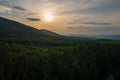 Aerial view of green pine forest with dark spruce trees covering mountain hills at sunset. Nothern woodland scenery from