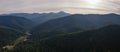 Aerial view of green pine forest with dark spruce trees covering mountain hills at sunset. Nothern woodland scenery from