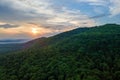 Aerial view of green pine forest with dark spruce trees covering mountain hills at sunset. Nothern woodland scenery from