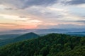 Aerial view of green pine forest with dark spruce trees covering mountain hills at sunset. Nothern woodland scenery from