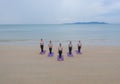 Aerial view of group of Asian women in yoga class club doing exercise and yoga at natural beach and sea coast outdoor in sport and Royalty Free Stock Photo