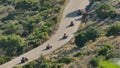 Aerial view of a group of people enjoying a motorcycle ride down a winding mountain trail