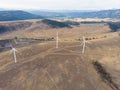 Aerial view of group of wind turbines on beautiful sunny mountain landscape. Clean energy power concept. Road through mountain eco