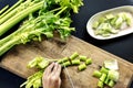 Aerial view of hands with knife cutting celery on wooden cut boa