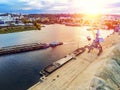 Aerial view of heavy crane loading bulk goods at Dnieper river cargo port terminal in Kiev at evening sunset time. tugboat pushes Royalty Free Stock Photo