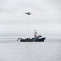 Aerial view of a helicopter lifting supplies from a research vessel in Umnak, Alaska