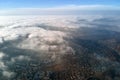 Aerial view from high altitude of distant city covered with puffy cumulus clouds forming before rainstorm. Airplane