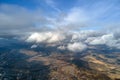 Aerial view from high altitude of distant city covered with puffy cumulus clouds forming before rainstorm. Airplane Royalty Free Stock Photo
