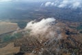 Aerial view from high altitude of distant city covered with puffy cumulus clouds forming before rainstorm. Airplane Royalty Free Stock Photo