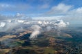 Aerial view from high altitude of distant city covered with puffy cumulus clouds forming before rainstorm. Airplane Royalty Free Stock Photo