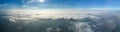 Aerial view from high altitude of distant city covered with puffy cumulus clouds forming before rainstorm. Airplane Royalty Free Stock Photo