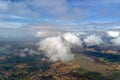 Aerial view from high altitude of distant city covered with puffy cumulus clouds forming before rainstorm. Airplane Royalty Free Stock Photo