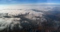 Aerial view from high altitude of distant city covered with puffy cumulus clouds forming before rainstorm. Airplane Royalty Free Stock Photo