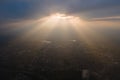 Aerial view from high altitude of distant city covered with puffy cumulus clouds forming before rainstorm in evening