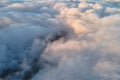 Aerial view from high altitude of distant city covered with puffy cumulus clouds forming before rainstorm in evening