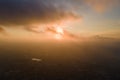 Aerial view from high altitude of distant city covered with puffy cumulus clouds forming before rainstorm in evening