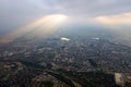 Aerial view from high altitude of distant city covered with puffy cumulus clouds forming before rainstorm in evening