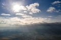 Aerial view from high altitude of distant city covered with puffy cumulus clouds forming before rainstorm in evening