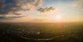 Aerial view from high altitude of distant city covered with puffy cumulus clouds forming before rainstorm in evening