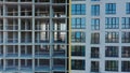 Aerial view of high residential apartment building under construction. Many windows on new apartment building facade