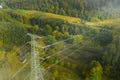 Aerial view of the high voltage power lines and high voltage electric transmission on the terrain surrounded by trees at Royalty Free Stock Photo