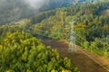 Aerial view of the high voltage power lines and high voltage electric transmission on the terrain surrounded by trees at