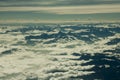 A aerial view of himalayan black silhouettes desert mountains with snowy peaks under white clouds and blue sky