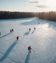 Aerial view of hockey players on a frozen lake, surrounded by a forest at dusk.