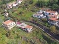 an aerial view of houses and small farms in the steep hillside valley between funchal and madeira with small fields and a road