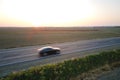 Aerial view of intercity road with blurred fast driving environment friendly electric car at sunset. Top view from drone Royalty Free Stock Photo