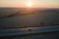 Aerial view of intercity road with blurred fast driving environment friendly electric car at sunset. Top view from drone Royalty Free Stock Photo