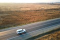 Aerial view of intercity road with blurred fast driving environment friendly electric car at sunset. Top view from drone Royalty Free Stock Photo
