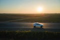 Aerial view of intercity road with blurred fast driving environment friendly electric car at sunset. Top view from drone Royalty Free Stock Photo