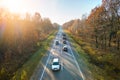 Aerial view of intercity road with fast driving cars between autumn forest trees at sunset. Top view from drone of Royalty Free Stock Photo